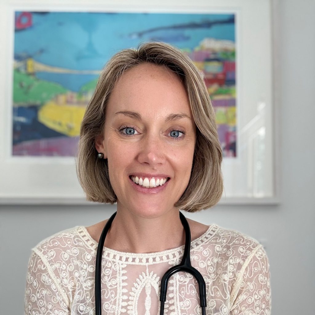 Dr Jessica Dawkins smiles at the camera. she has short blonde hair and is wearing a stethoscope around her neck.